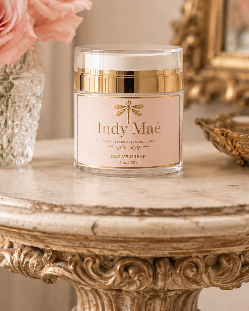 Jar of Indy Maé cream on a decorative table with pink roses and a mirror in the background